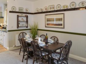 a dining room table with chairs and a bottle of wine at Quarryman's Cottage in Belford
