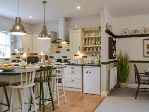 a kitchen with white cabinets and a table and chairs at Quarryman's Cottage in Belford +20 photos