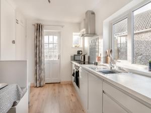 a kitchen with white cabinets and a sink and a window at Heritage Cottage in Flamborough