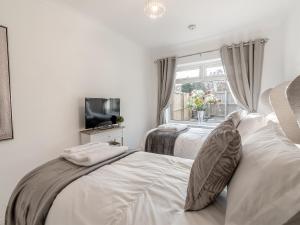 a white bedroom with two beds and a window at Heritage Cottage in Flamborough