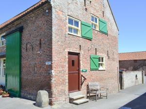 a brick building with a door and a bench on a street at Belgian Cottage in Sewerby