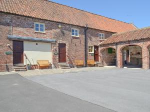 a group of brick buildings with benches in front of them at Belgian Cottage in Sewerby