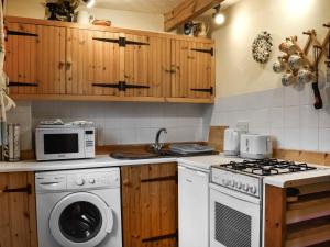 a kitchen with a stove and a washing machine at Poppy Cottage in Halesworth