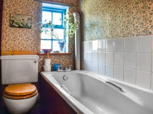 a bathroom with a bath tub and a toilet at Poppy Cottage in Halesworth