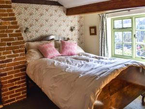 a bedroom with a bed with pink pillows on it at Poppy Cottage in Halesworth