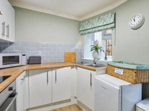 a kitchen with white cabinets and a clock on the wall at Cobblers Cottage in Barnard Castle