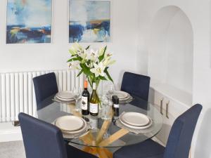 a dining room with a glass table and blue chairs at Station Cottage in Silverdale
