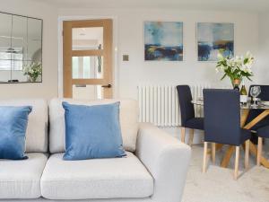 a white couch with blue pillows in a living room at Station Cottage in Silverdale