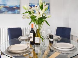 a glass table with a vase of flowers and wine bottles at Station Cottage in Silverdale