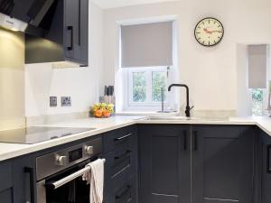 a kitchen with black cabinets and a clock on the wall at Station Cottage in Silverdale +10 photos