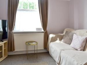 Una sala de estar con un sofá y una ventana. en Say Shells, en Filey