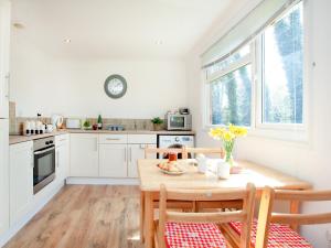 eine Küche mit einem Holztisch mit Stühlen und einer Uhr in der Unterkunft Lodge 133 - Uk43196 in Saint Merryn