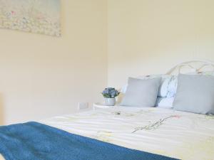 a white bed with blue and white sheets and pillows at Typicca Farmhouse in Brechfa