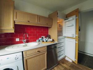 una cucina con lavandino e parete di piastrelle rosse di Borrowdale Cottage a Brough