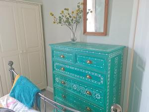 a green dresser with a vase on top of it at Hysryb Cottage in Cardiff