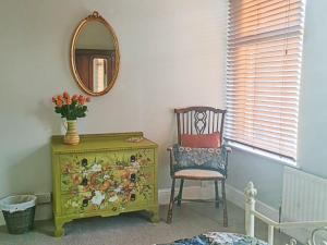a room with a chair and a dresser and a mirror at Hysryb Cottage in Cardiff