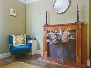a living room with a fireplace with a blue chair and a mirror at Hysryb Cottage in Cardiff