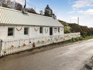 a white house with a fence on the side of a road at The Captains in Bettyhill +7 photos