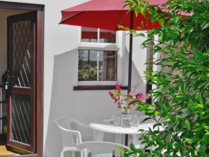a white table with a red umbrella and white chairs at Murton Farm Cottage in Bishopston +2 photos