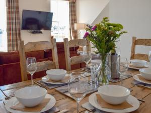a wooden table with bowls and glasses and flowers on it at Harbourside Apartment in Anstruther
