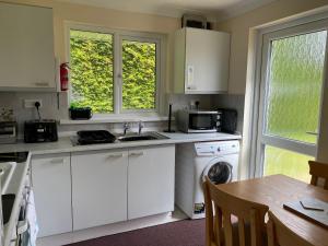 cocina con armarios blancos, mesa y ventanas en Pencarrow - B6521, en Saint Cleer