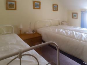 a bedroom with two beds and a chair in it at Pencaire in Helston