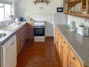 a kitchen with a sink and a stove at Pencaire in Helston