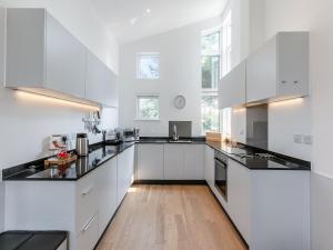 a kitchen with white cabinets and black counter tops at Aquamarine in Carbis Bay