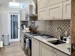 Una cocina con gabinetes blancos y un horno de estufa. en Admiral's Lookout, en Ilfracombe