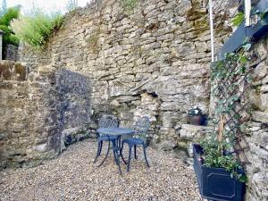 a table and two chairs sitting next to a stone wall at T'owd Man's Cottage in Bonsall