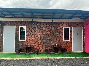 a stone wall with three tables in front of a building at Avina's Standard Room in Setiu
