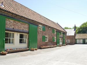 a row of brick buildings with green doors and windows at Shire Cottage in Sewerby
