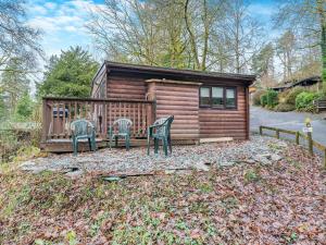 une cabane en rondins avec deux chaises et une maison dans l'établissement Seathwaite Tarn, à Ambleside