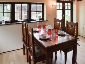 une salle à manger avec une table, des chaises et des fenêtres dans l'établissement Capri Cottage, à Winterton-on-Sea