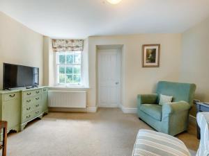 a living room with a chair and a television at South Wing Cottage in Rumleigh