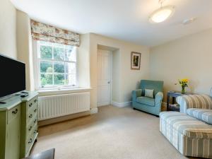 a living room with a couch and a tv at South Wing Cottage in Rumleigh