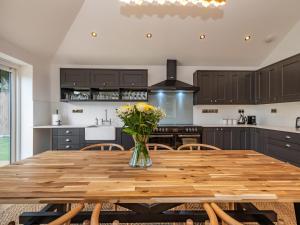 een keuken met een houten tafel en een vaas met bloemen bij Clematis Cottage in Thorpe Market