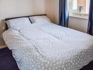ein Bett mit einer weißen Bettdecke und einem Fenster in der Unterkunft Harley's Beach House in Scratby