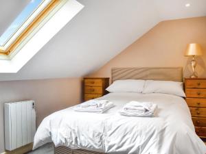 ein Schlafzimmer mit einem Bett mit weißen Laken und einem Fenster in der Unterkunft Swift Cottage - Uk47527 in Roxby