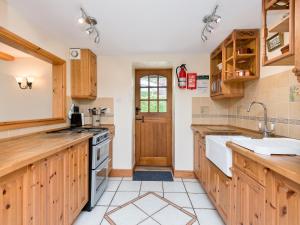 a kitchen with wooden cabinets and a sink and a door at Coach House in Wareham