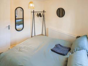 un lit dans une chambre avec un miroir et un oreiller dans l'établissement Curiosity Cottage, à Eyam