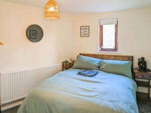 une chambre avec un lit avec des draps bleus et une fenêtre dans l'établissement Curiosity Cottage, à Eyam