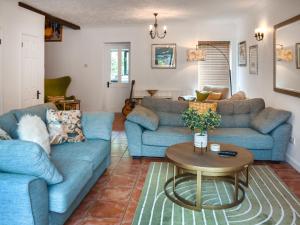 a living room with blue couches and a table at Shetland Cottage in Stalham