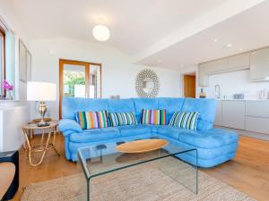 Un sofá azul en una sala de estar con una mesa. en Beachbreak - Uk42996, en Woolacombe