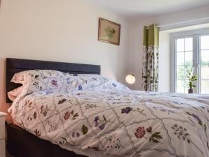 a bedroom with a bed with a floral bedspread at Pickled Onion Cottage in Taunton +15 photos
