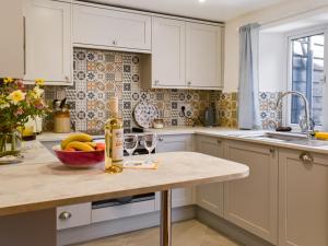 a kitchen with white cabinets and a bowl of fruit on a counter at Pickled Onion Cottage in Taunton