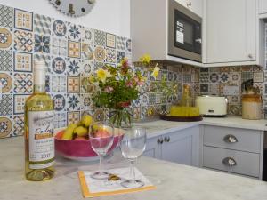 a bottle of wine and two wine glasses on a kitchen counter at Pickled Onion Cottage in Taunton