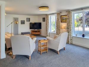 a living room with two white chairs and a television at Beacon Cottage in Ivegill