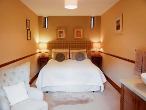 ein Schlafzimmer mit einem weißen Bett und einem Stuhl in der Unterkunft Garden Cottage in Pooley Bridge