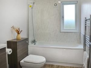 a bathroom with a white tub and a toilet and a window at Harwood Lodge - Uk45602 in Wilberfoss +5 photos